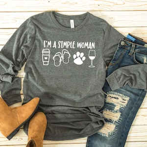 Könnte beinhalten: Graues Langarmshirt mit dem Text "I'm a simple woman" und Symbolen für eine Tasse Kaffee, Flip-Flops, einen Pfotenabdruck und ein Weinglas.