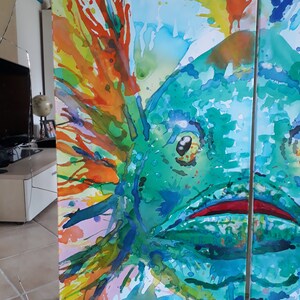 May include: Abstract watercolour painting of a fish in shades of teal, green, orange, and yellow. The artwork is divided into three panels, with the fish's eye and mouth visible. Splashes of colour create a dynamic and vibrant composition.
