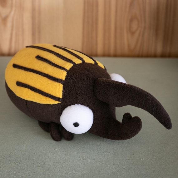 A lovingly handmade giant Hercules beetle plush that nails the real insect's anatomy — this is naturalist shelf decor, not a kiddie toy.
