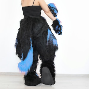 May include: A black and blue furry costume set, including leg coverings, hand covers, and foot covers. The costume features long, shaggy black fur with blue and pink accents. The foot covers have a flat, black sole.