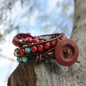 May include: A multi-strand leather bracelet with red beads and a large wooden button closure.