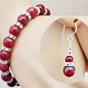 May include: A beaded bracelet and a matching drop earring featuring faceted deep red spherical beads. The bracelet alternates these red beads with silver-toned spacers. The earring hangs from a silver-toned hook and includes smaller silver beads.