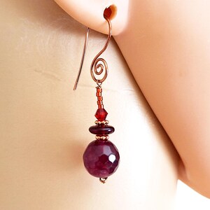 May include: Copper wire earrings with a faceted purple gemstone, a red crystal bead, and copper beads.