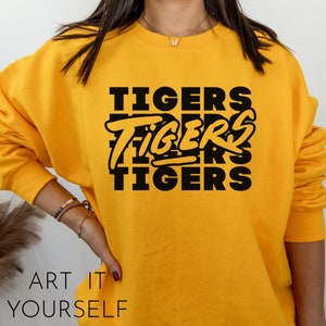 May include: Yellow sweatshirt with black text that reads "TIGERS" repeated three times in a stacked design.