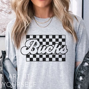 May include: Gray t-shirt with a black and white checkered design and the word "Bucks" in a retro font.