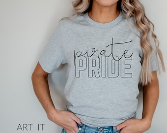 Puede incluir: Una camiseta gris con el texto "pirate pride" en letras negras. El texto está en una fuente estilizada con la palabra "pirate" en cursiva y la palabra "pride" en letras mayúsculas.