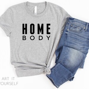 May include: A gray t-shirt with black text that reads "HOME BODY".