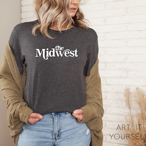 Puede incluir: Una camiseta gris oscuro con el texto "the Midwest" impreso en blanco en la parte delantera.