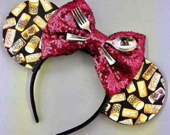 May include: Red sequined bow with a silver fork and spoon, attached to a black headband with a cork and wine bottle print.