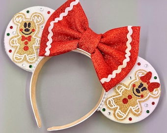 May include: Red and white bow headband with gingerbread man ears. The gingerbread men are decorated with gold glitter and red and green sprinkles.