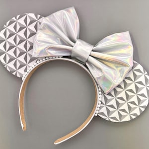 May include: Silver iridescent bow headband with a geometric pattern on the ears.