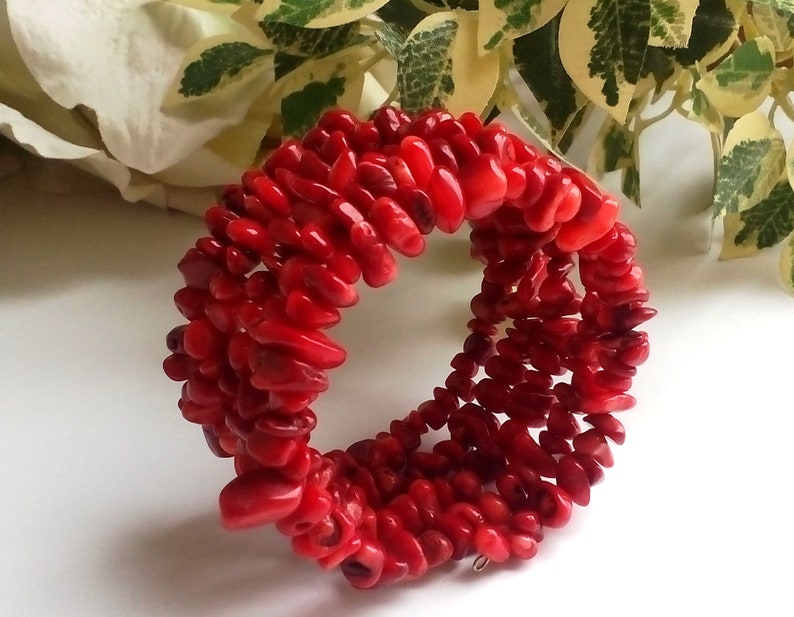 Puede incluir: Un brazalete de coral rojo hecho de peque&ntilde;as cuentas de forma irregular. El brazalete est&aacute; apilado con m&uacute;ltiples filas de cuentas.