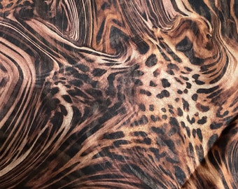 May include: Abstract fabric with a brown and tan leopard print pattern. The fabric has a swirling, marbled effect.