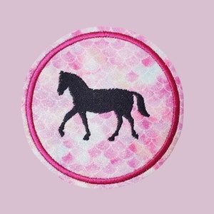 Könnte beinhalten: Ein runder rosa und weißer Patch mit einer schwarzen Silhouette eines Pferdes. Der Patch hat einen rosa Rand und einen glitzernden, schillernden Hintergrund.