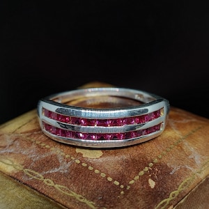 Peut inclure: Une bague en argent avec deux rangées de pierres précieuses roses carrées.