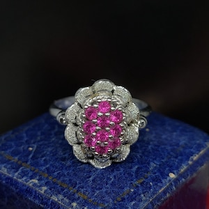 May include: A silver ring featuring a cluster of pink gemstones set in a floral design.