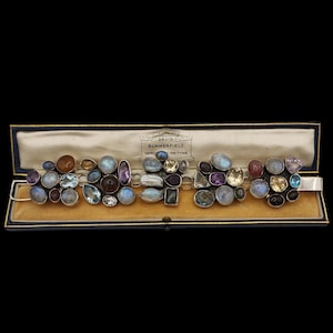 May include: A silver bracelet featuring an assortment of colourful gemstones, such as amethyst, moonstone, and citrine. The bracelet is presented in a velvet-lined box with the label "David Summerfield, Newcastle-on-Tyne."