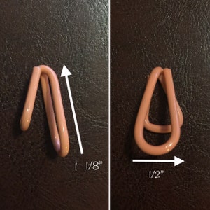 May include: Two pink metal curtain rings, one measuring 1/8 inch in height and the other measuring 1/2 inch in width.