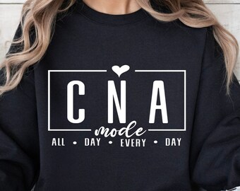 May include: Black sweatshirt with white text that reads "CNA mode all day every day" with a small heart above the text.