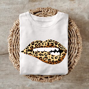Puede incluir: Camiseta blanca con un diseño de labios de estampado de leopardo.