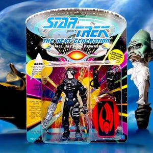 May include: A Star Trek: The Next Generation Borg action figure in its original packaging. The figure is black and silver with a red shield and additional accessories. The packaging features the Star Trek logo and text.