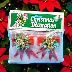 May include: A pack of Christmas decorations with two red bow ornaments. Each bow has a gold angel and the word "Gloria". The package is labelled "Christmas Decoration" and "Made in Hong Kong".