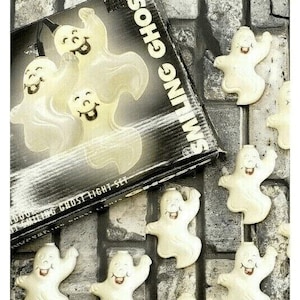 May include: A vintage Halloween Smiling Ghost Light Set. The box features the words "Smiling Ghosts" and "Ghost Light Set". The set includes several smiling ghost-shaped lights with black smiles and red tongues. The lights are white and appear to glow.