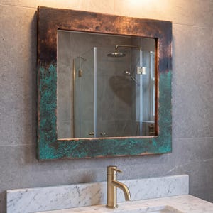 May include: A square wall mirror featuring a wide, flat frame with a weathered, oxidized finish that transitions from a dark brown metallic tone at the top to a vibrant, textured teal green patina across the bottom and side sections.