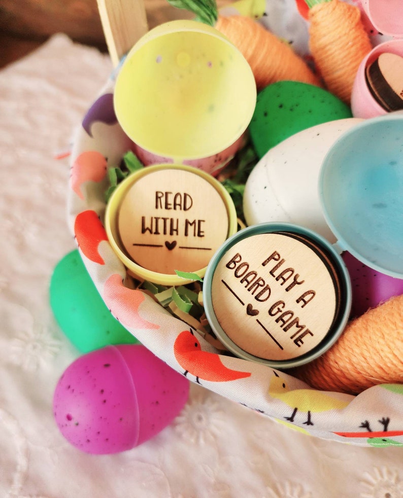 May include: A basket filled with colorful plastic Easter eggs, yarn, and wooden tokens with the text "Read with me" and "Play a board game".
