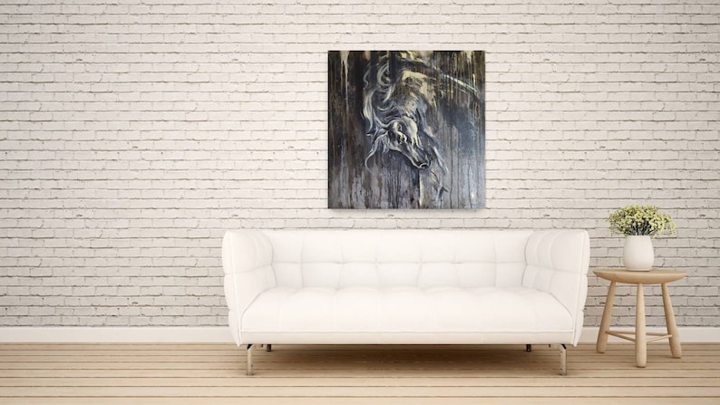 K&ouml;nnte beinhalten: Ein wei&szlig;es Sofa mit einer wei&szlig;en Backsteinwand im Hintergrund. Ein Gem&auml;lde eines wei&szlig;en Pferdekopfes auf einem dunklen Holzgrund h&auml;ngt &uuml;ber dem Sofa. Ein kleiner Holztisch mit einer Topfpflanze steht rechts neben dem Sofa.