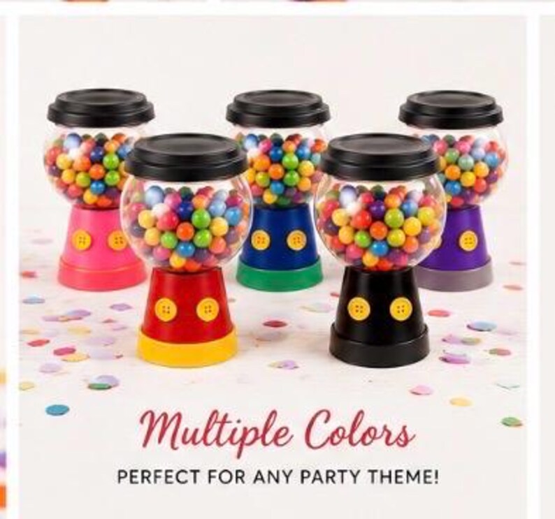 May include: Five gumball machine containers in various colours, including red, pink, blue, green, and purple, each with a black lid. The containers are filled with assorted gumballs. Text reads "Multiple Colors".