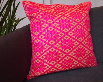 Pode incluir: Uma almofada rosa e dourada com um padrão geométrico. A almofada é feita de um tecido macio e tecido e tem uma forma quadrada.