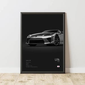 May include: Framed print featuring a silver Lexus LFA sports car against a black background. The car is positioned at a slight angle, showcasing its front and side. Text on the print includes "Lexus LFA" and specifications. The print is in a black frame.