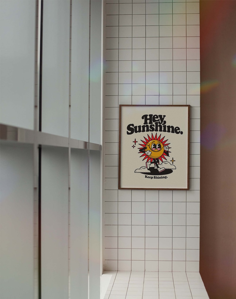 May include: A framed print with a yellow cartoon sun with a smiling face and the text "Hey Sunshine. Keep Shining."