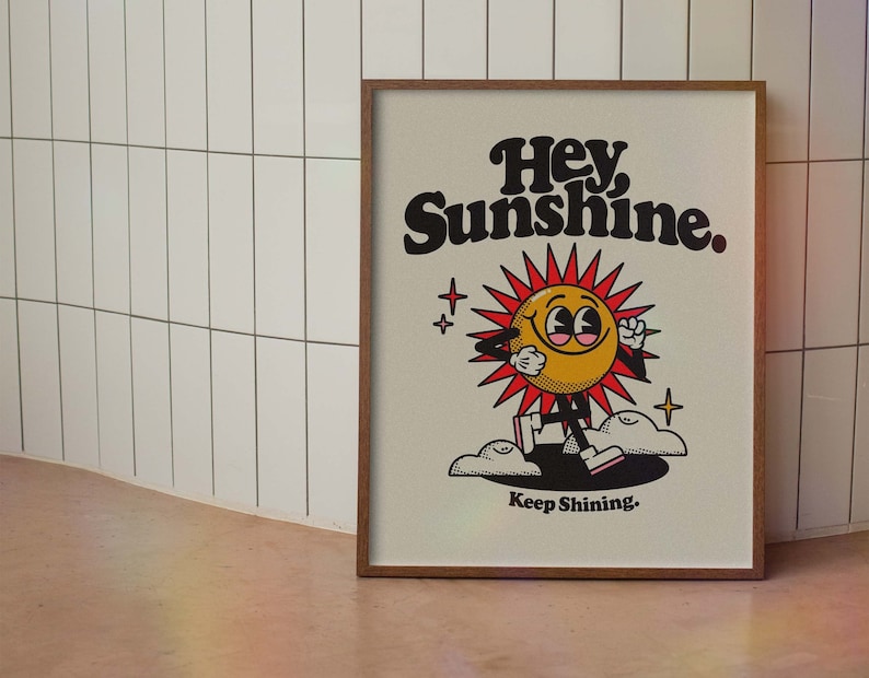 May include: A framed print with a cartoon sun character with the text "Hey Sunshine. Keep Shining."