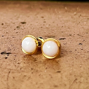 Puede incluir: Un par de pendientes de botón de oro con piedras redondas blancas.