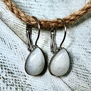 Könnte beinhalten: Ein Paar silberne Tropfenohrringe mit weißen Steinakzenten.