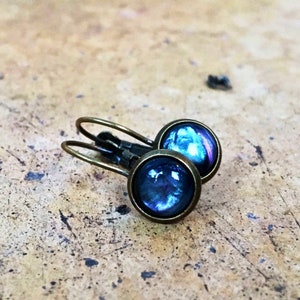 May include: A pair of bronze hoop earrings with blue iridescent glass cabochons.