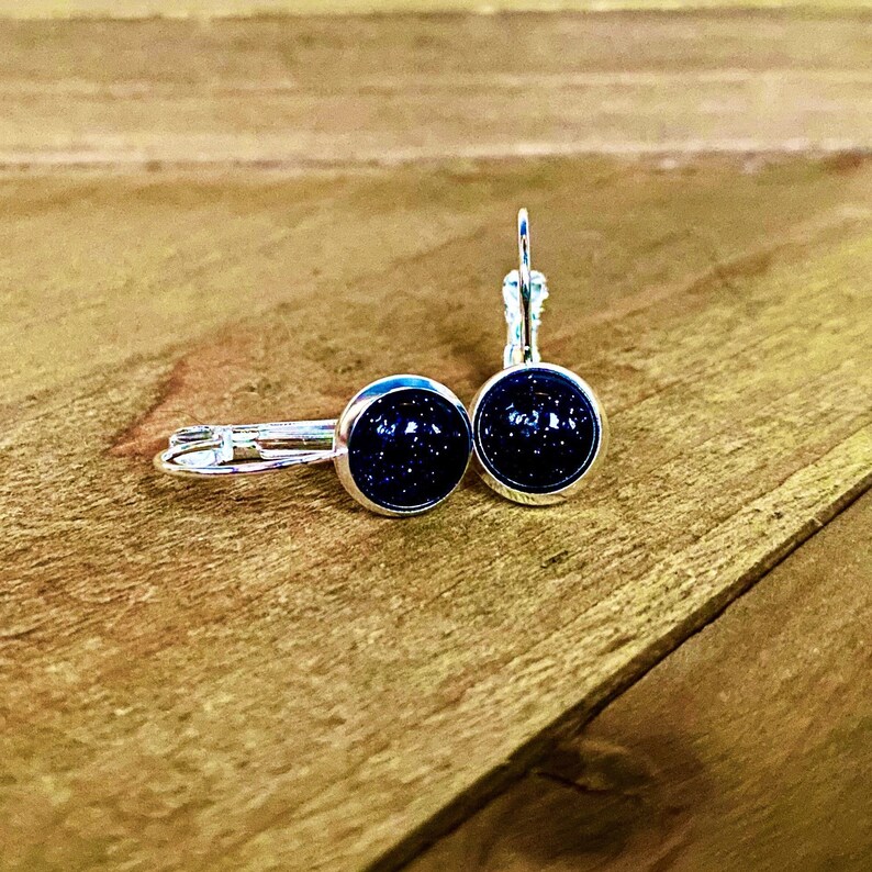 May include: A pair of silver hoop earrings with black glitter round cabochon stones.