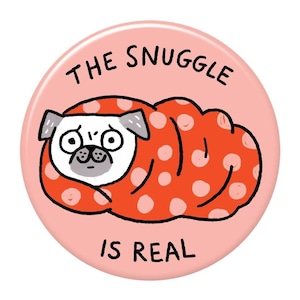 Peut inclure: Un bouton rose avec un carlin blanc enveloppé dans une couverture rouge à pois blancs. Le texte "THE SNUGGLE IS REAL" est imprimé sur le bouton.