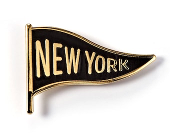 May include: A black and gold enamel pin shaped like a pennant with the words "NEW YORK" in gold lettering.