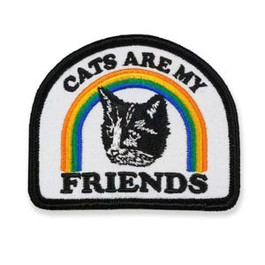 May include: Embroidered patch with a black and white cat face, a rainbow, and the text "CATS ARE MY FRIENDS" in black letters. The patch has a white background and a black border. The patch is approximately 3 inches wide and 2.5 inches tall.