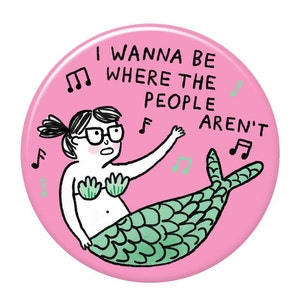 Puede incluir: Botón rosa con una sirena de dibujos animados que lleva gafas y un sujetador de concha verde. La sirena está cantando y el texto en el botón dice "Quiero estar donde la gente no está".