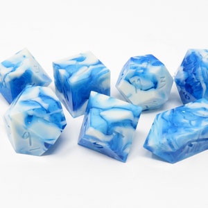 May include: Set of six blue and white marbled dice with black numbers. The dice are made of resin and have a swirling pattern.