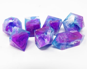 May include: Set of six iridescent dice with a blue and purple swirl pattern. The dice are made of resin and have a glittery finish.