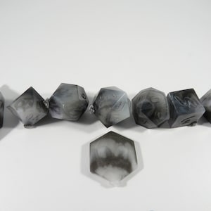 Puede incluir: Conjunto de siete dados negros y blancos con patrones de remolino. Los dados están hechos de resina y tienen una apariencia nublada y translúcida.