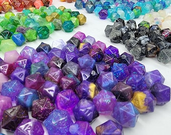 May include: A collection of purple, blue, and gold iridescent dice with glitter. The dice are made of resin and have a variety of patterns and designs.