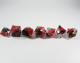 May include: Set of seven red and black dice with white numbers. The dice are translucent and have a swirling pattern.