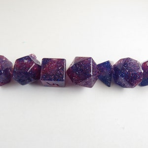 May include: Set of seven purple and blue dice with glitter embedded in the resin. The dice are various shapes, including a d4, d6, d8, d10, d12, and d20.