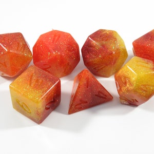 May include: Set of seven dice with a red and yellow glitter finish. The dice are numbered 1 through 6 and are perfect for tabletop games.